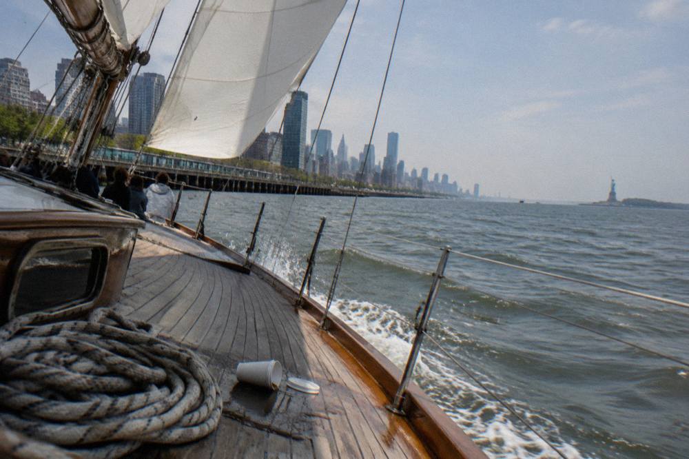 A schooner under sail on New York Harbor with the Statue of Liberty in the distance