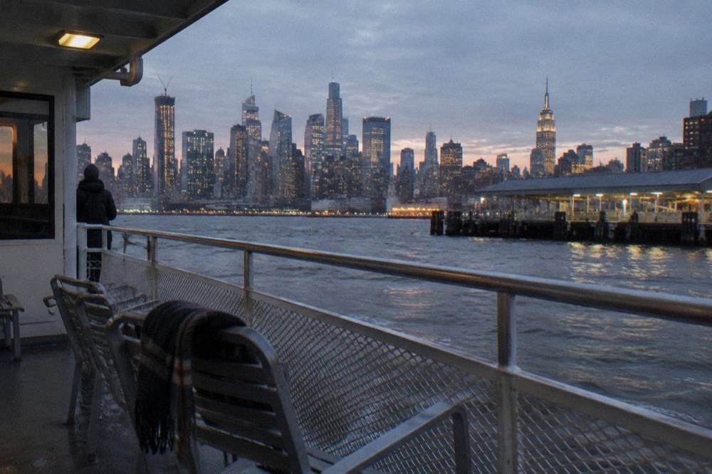 The Manhattan skyline at dusk seen across the Hudson River from the deck of a boat
