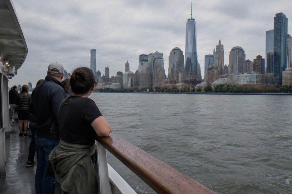 Passengers along the rail of a sightseeing boat watching the Manhattan skyline pass by