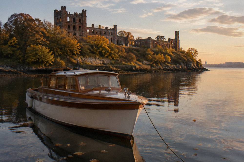 A wooden motor yacht on calm river water in late afternoon light