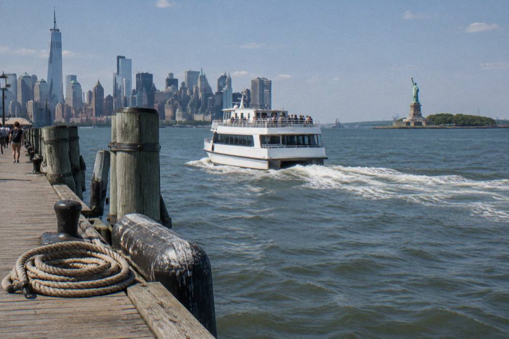 A sightseeing cruise boat passing close to the Statue of Liberty with Manhattan in the background