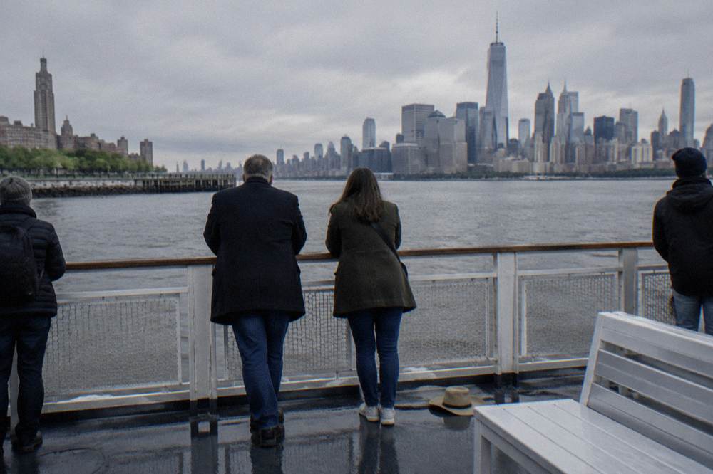 Passengers at the rail of a sightseeing boat watching the Manhattan skyline from the Hudson River