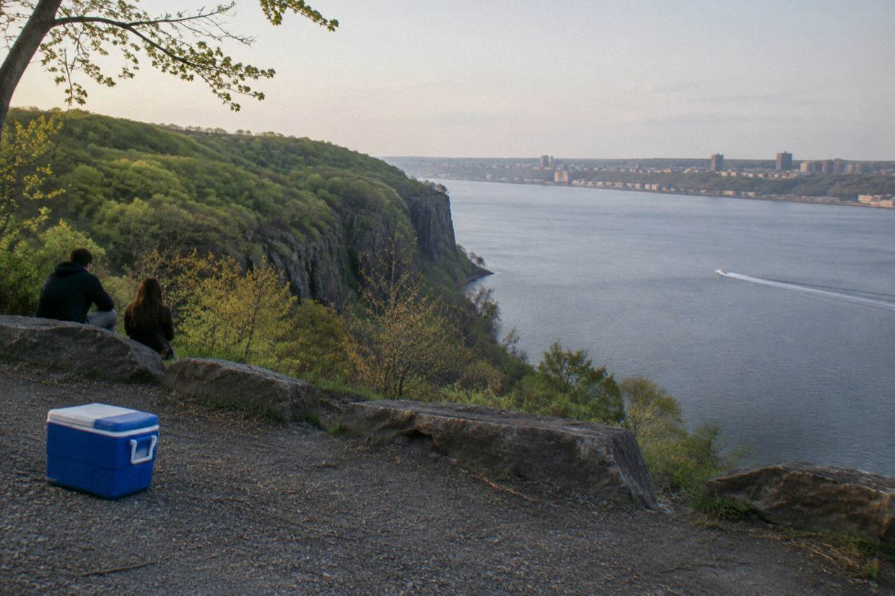 Wooded cliffs above a wide river with a small boat wake crossing the calm water