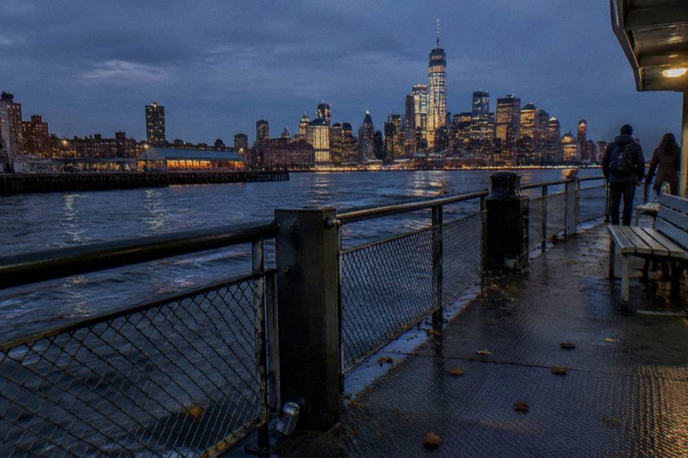 A ferry deck at golden hour with downtown towers glowing across the harbor water