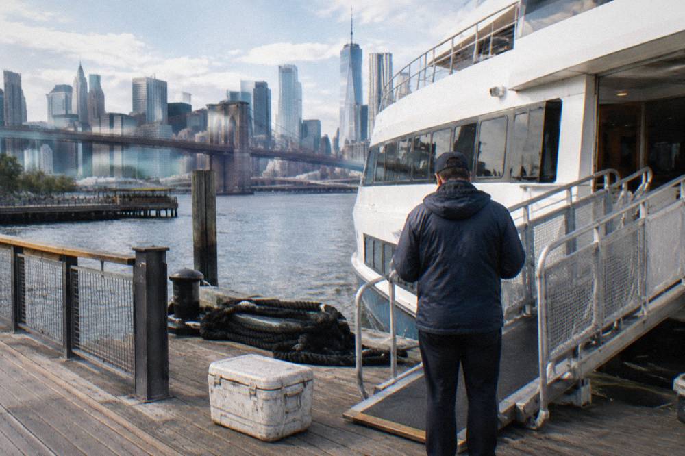 Crew member checking tickets at the base of a boarding ramp to a cruise vessel