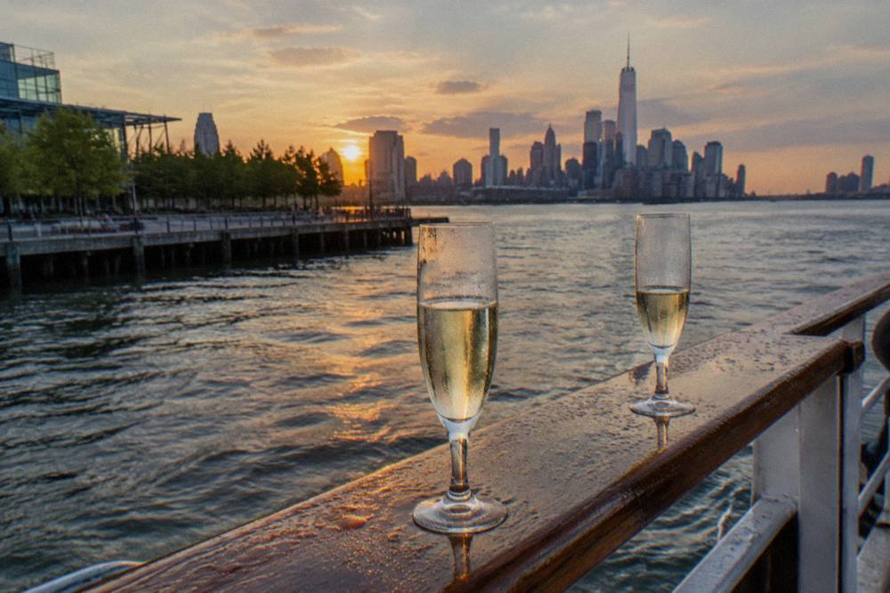 Two glasses of sparkling wine resting on a wooden deck rail with the harbor in the background