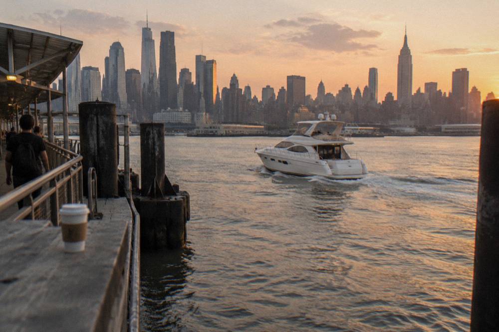 A classic motor yacht cruising past the Manhattan skyline on the Hudson River