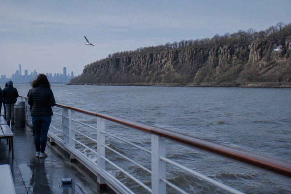 A sightseeing boat on the Hudson River with the Manhattan skyline and masts in view