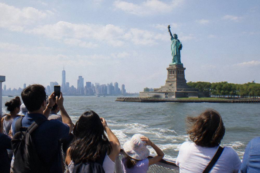 Passengers on an open deck of a boat viewing the Statue of Liberty from the water