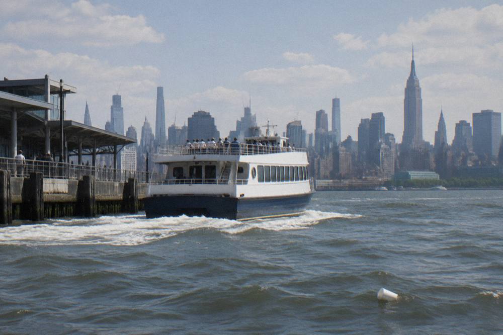 Sightseeing boat moving across the Hudson River with the Manhattan skyline behind it
