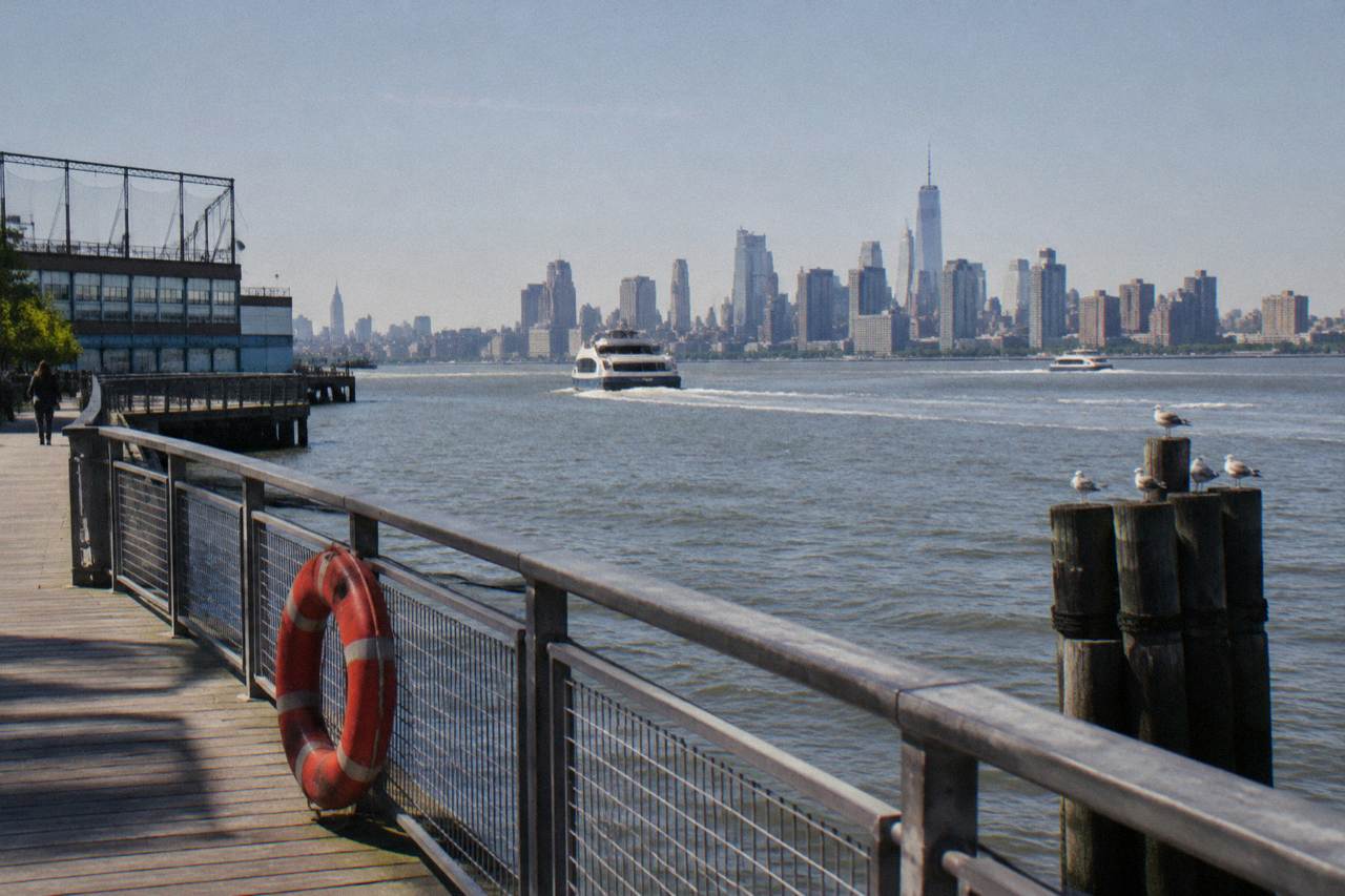 Wide view of the Hudson River from a Manhattan pier with the New Jersey shoreline across the water