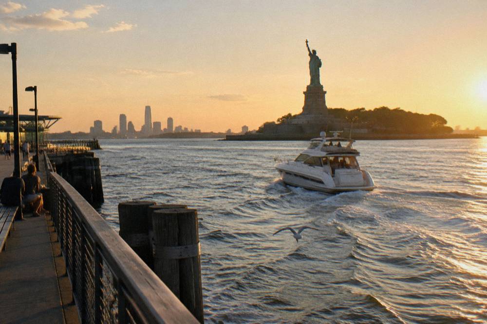A small yacht passing close to Liberty Island with the Statue of Liberty rising above the water