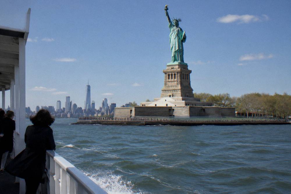 A sightseeing boat passing the Statue of Liberty at close range on open harbor water
