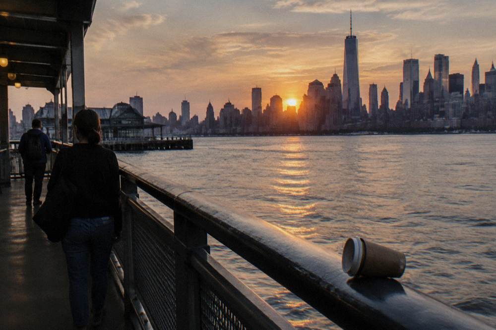 The sun setting behind the Manhattan skyline as seen from the Hudson River