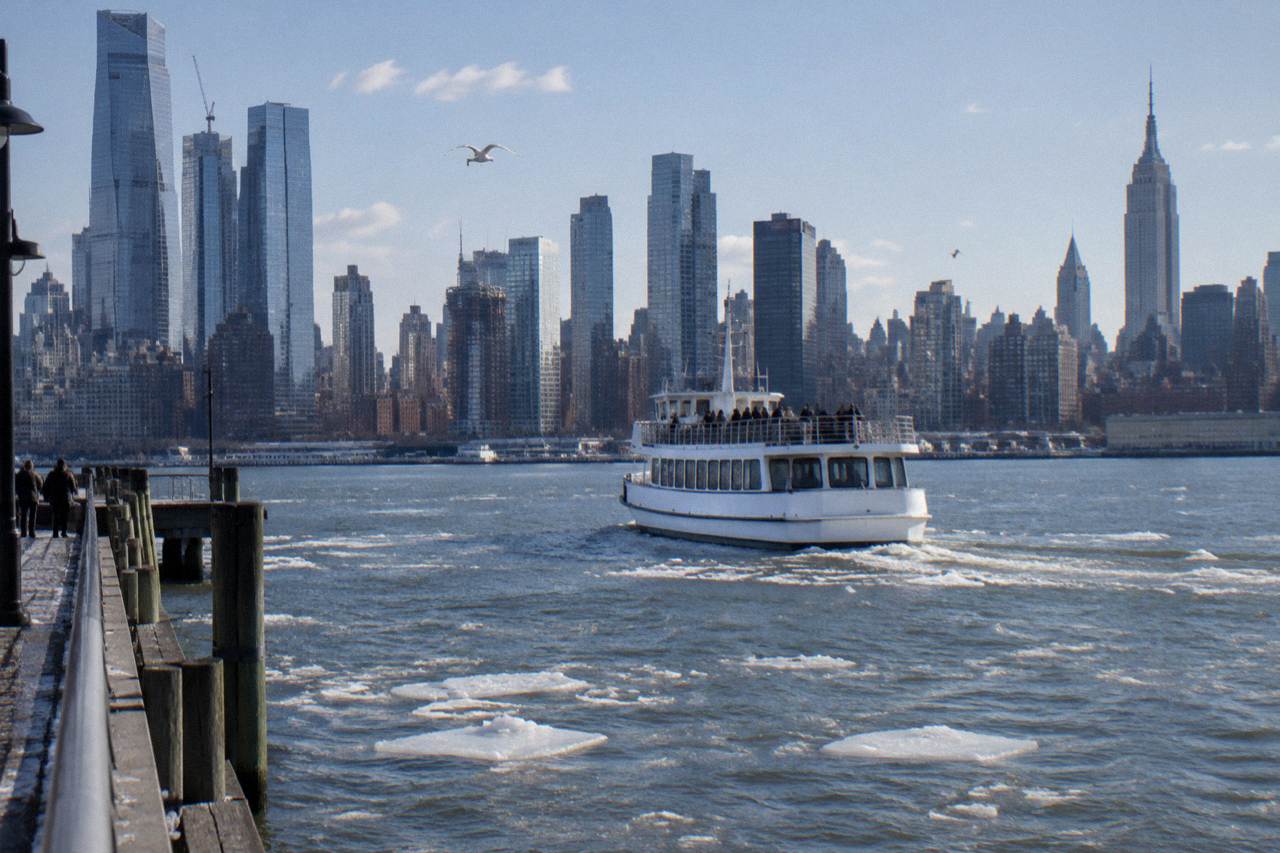 A sightseeing boat cruising past the Manhattan skyline on the Hudson River