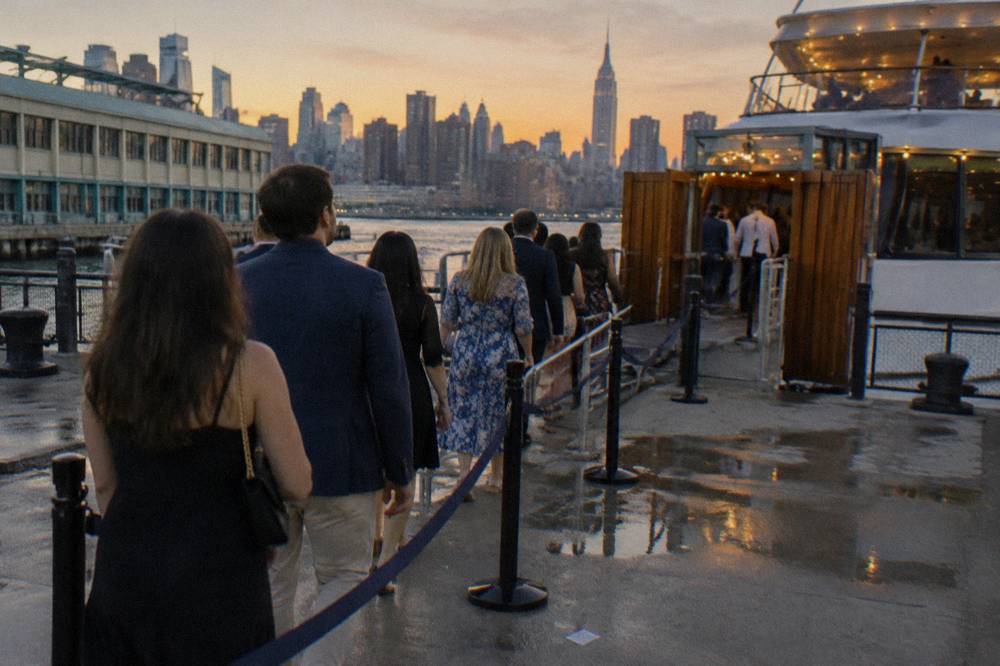A boarding queue of passengers at a pier gate with a cruise boat waiting at the dock