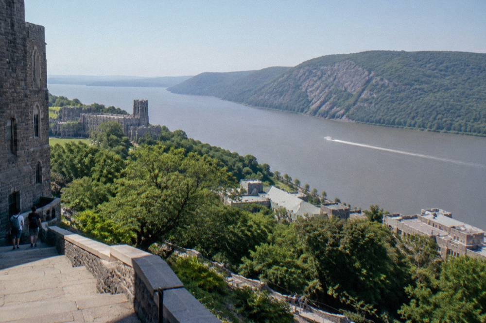 Wooded cliffs rising above a wide river with a small boat wake crossing the water