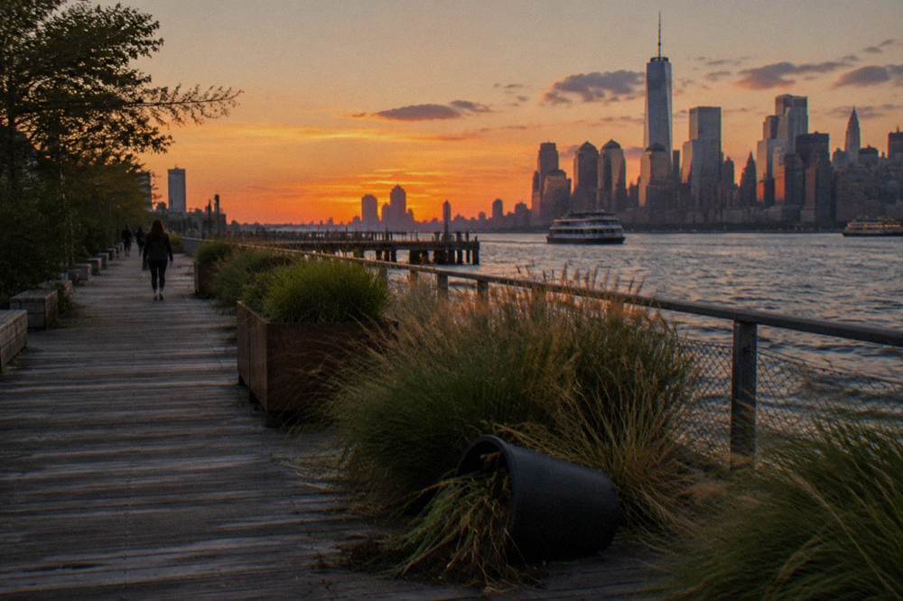 Reclaimed wooden pier with planted walkways extending over the river at dusk