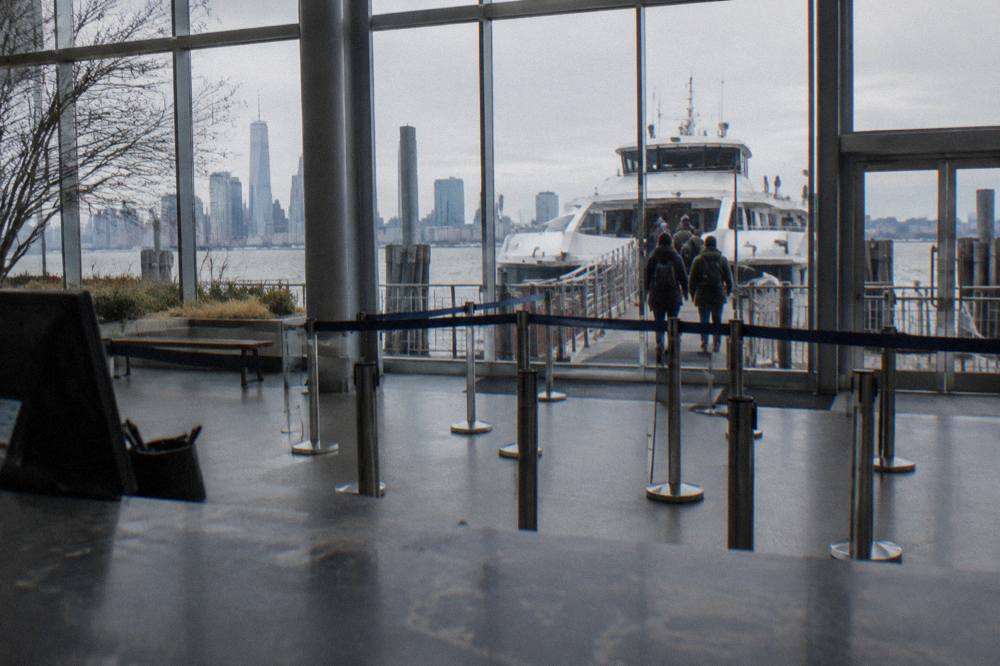 Ticket counter at a Manhattan cruise pier with a boat boarding in the background