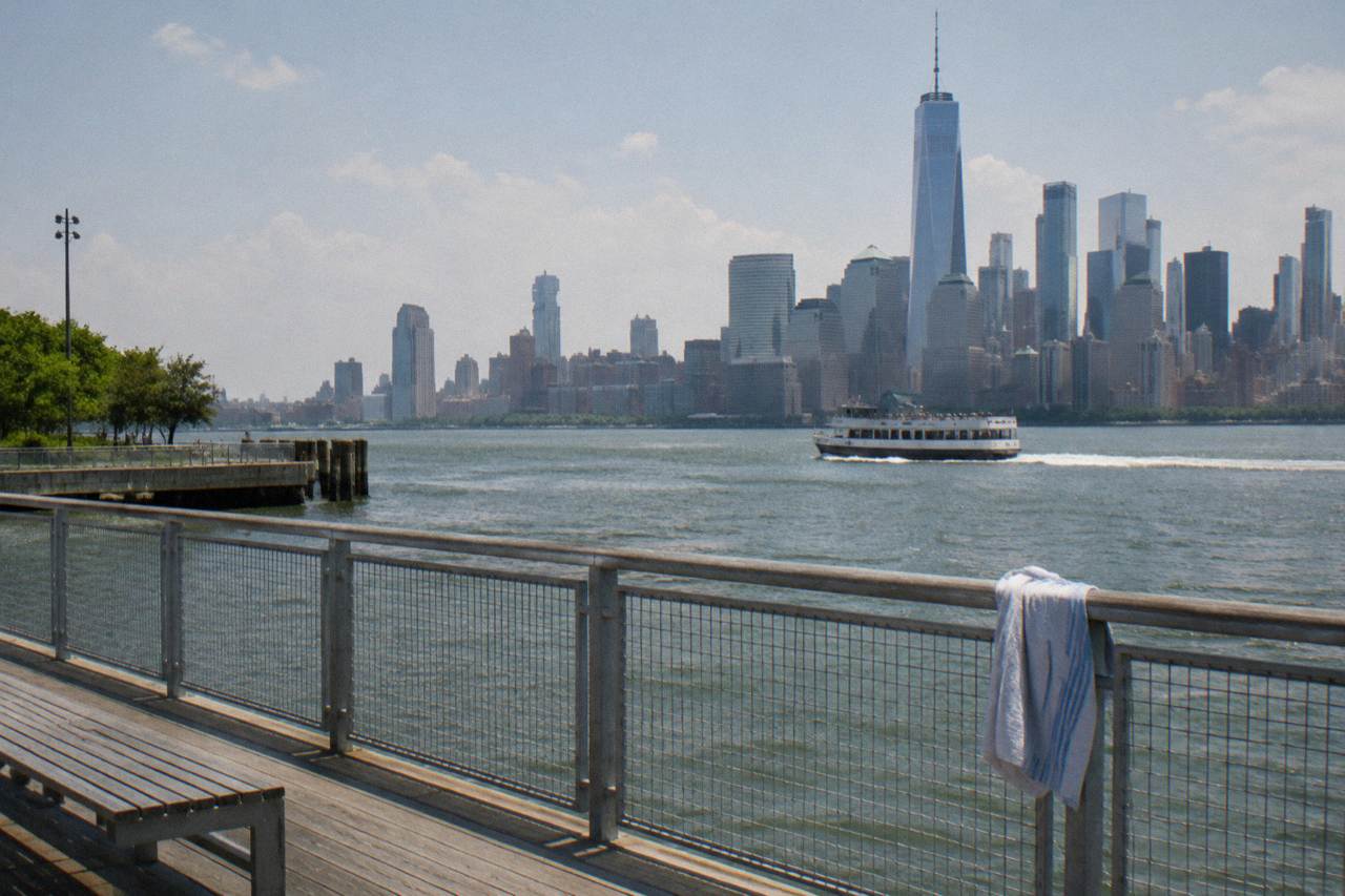 A sightseeing boat on the Hudson River with the Manhattan skyline behind it at midday