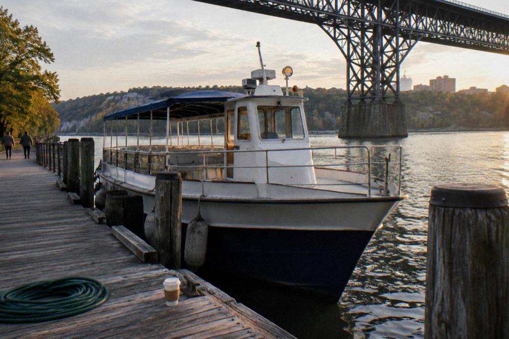 A passenger boat moored at a wooden dock on a wide river in late afternoon light