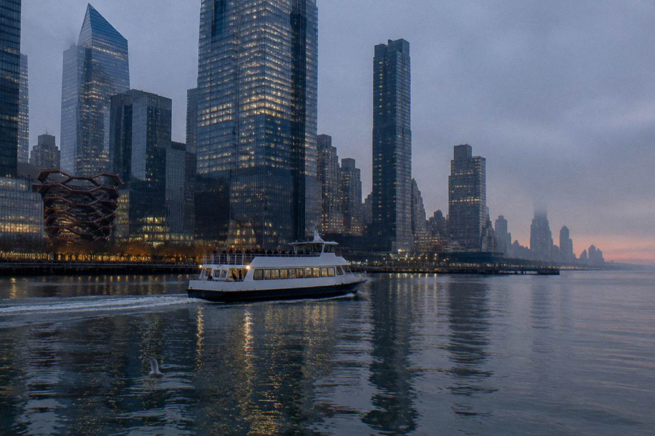 A sightseeing boat on the Hudson River with the Manhattan skyline behind it