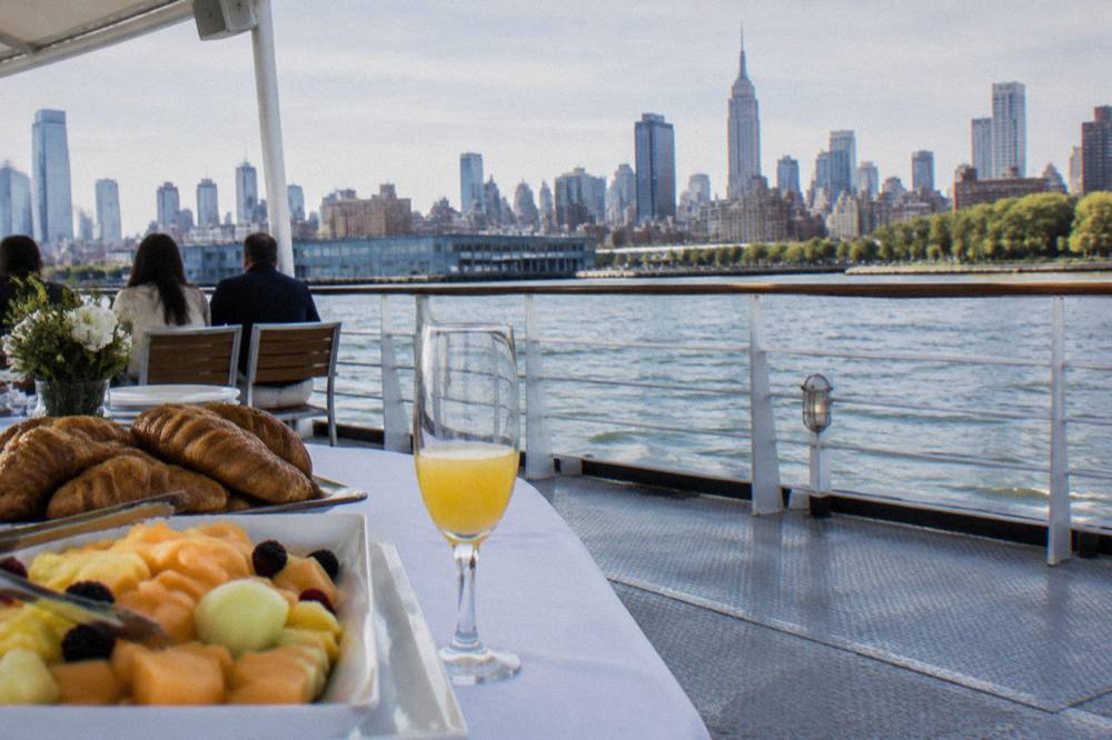 A brunch buffet table with pastries and fruit set up on the deck of a boat