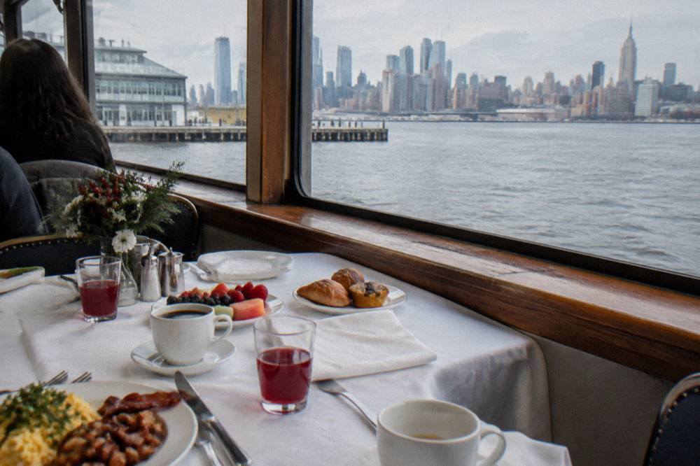 A holiday brunch table set aboard a yacht beside a window with the harbor beyond