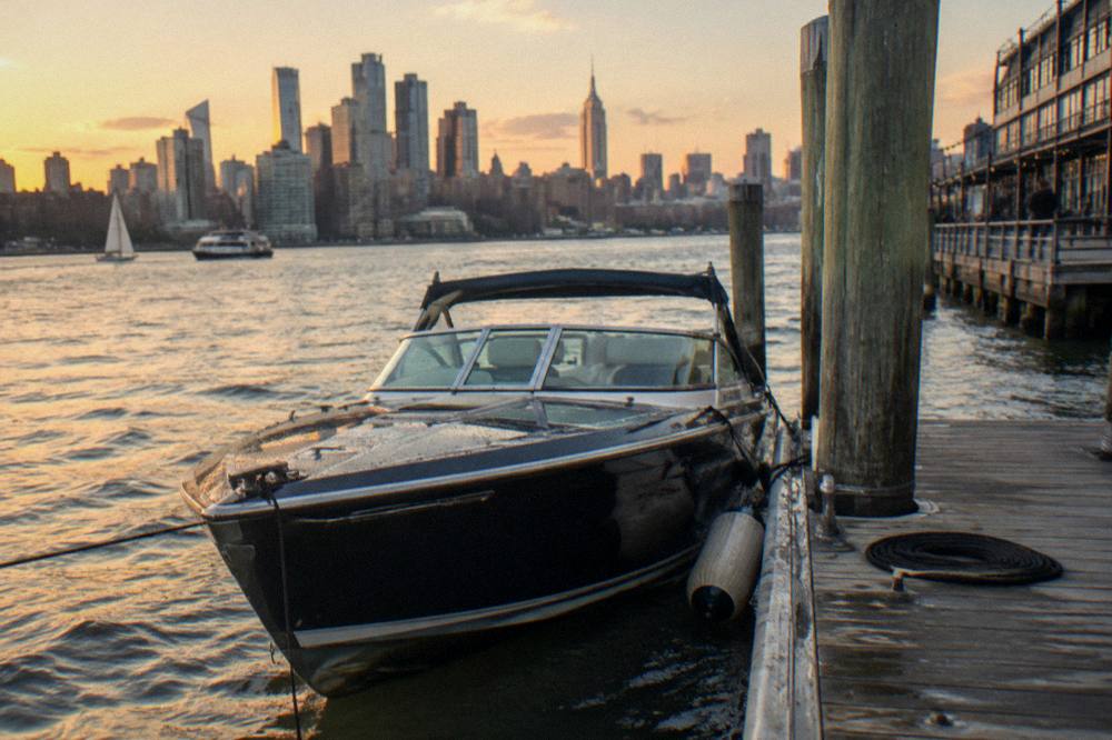 A sleek private speedboat moored at a Chelsea Piers dock at golden hour