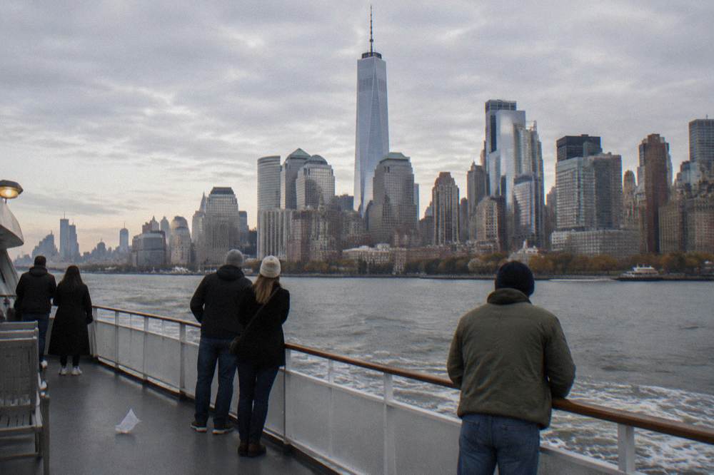 A group of passengers on the open deck of a private charter boat approaching the Manhattan skyline