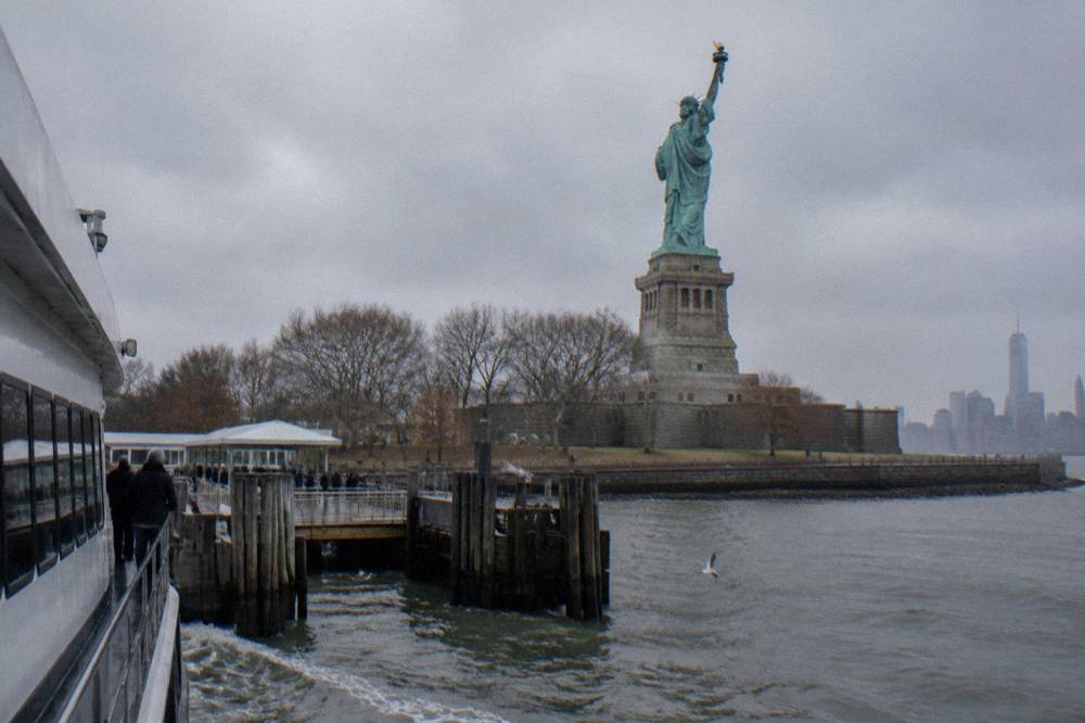 A sightseeing ferry passing close to Liberty Island with the Statue of Liberty towering above the deck