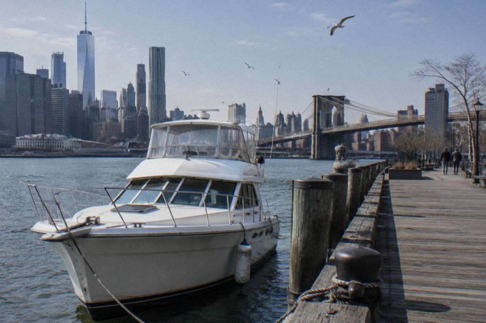 A wooden pier on the Manhattan waterfront with a classic motor yacht moored beside it