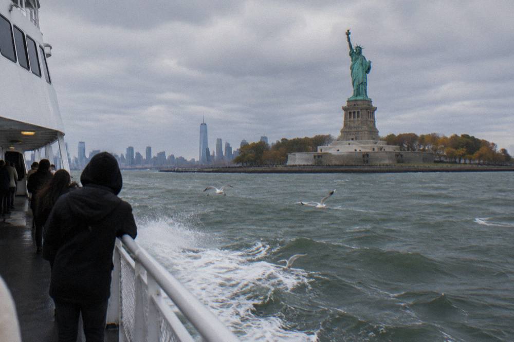 A ferry boat crossing New York Harbor toward the Statue of Liberty on a clear morning