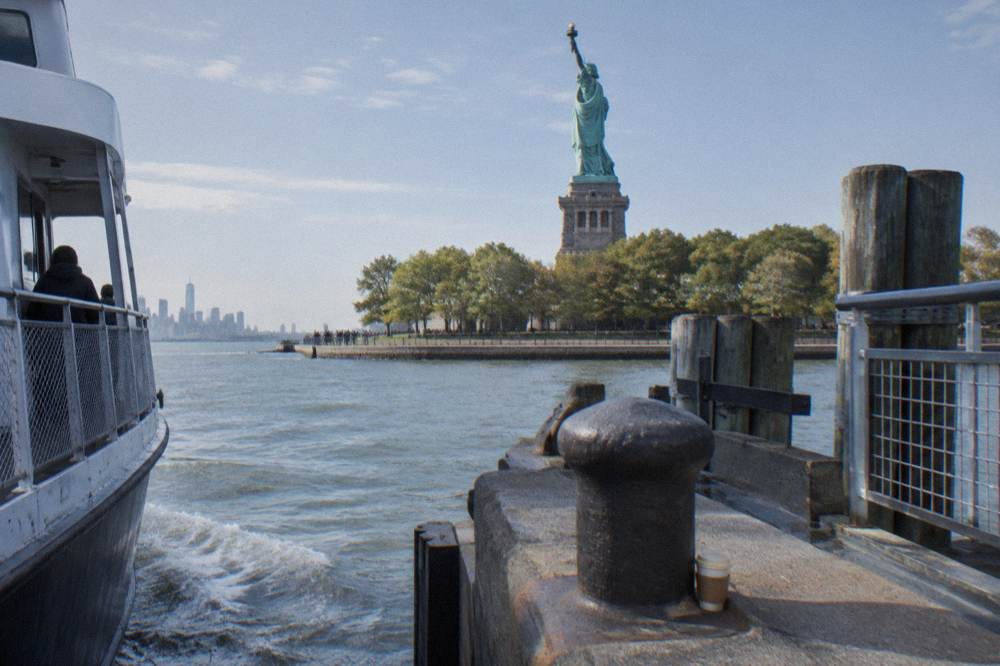 A ferry dock at Liberty Island with the statue rising above the trees