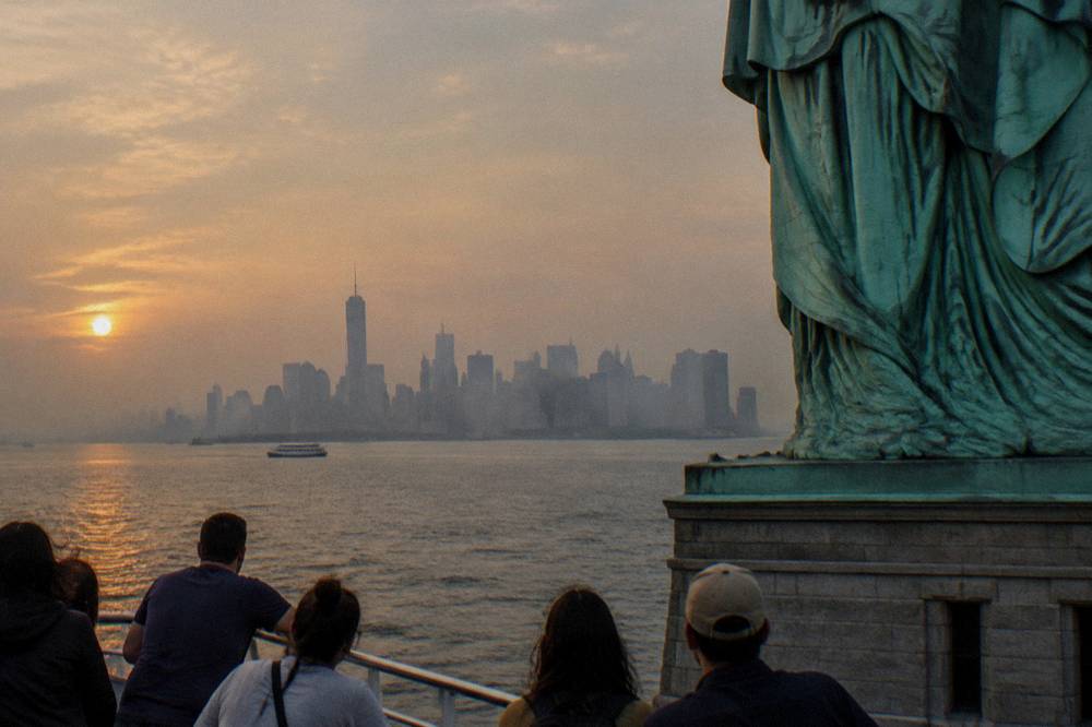 A sightseeing boat passing close to the Statue of Liberty with Manhattan in the distance