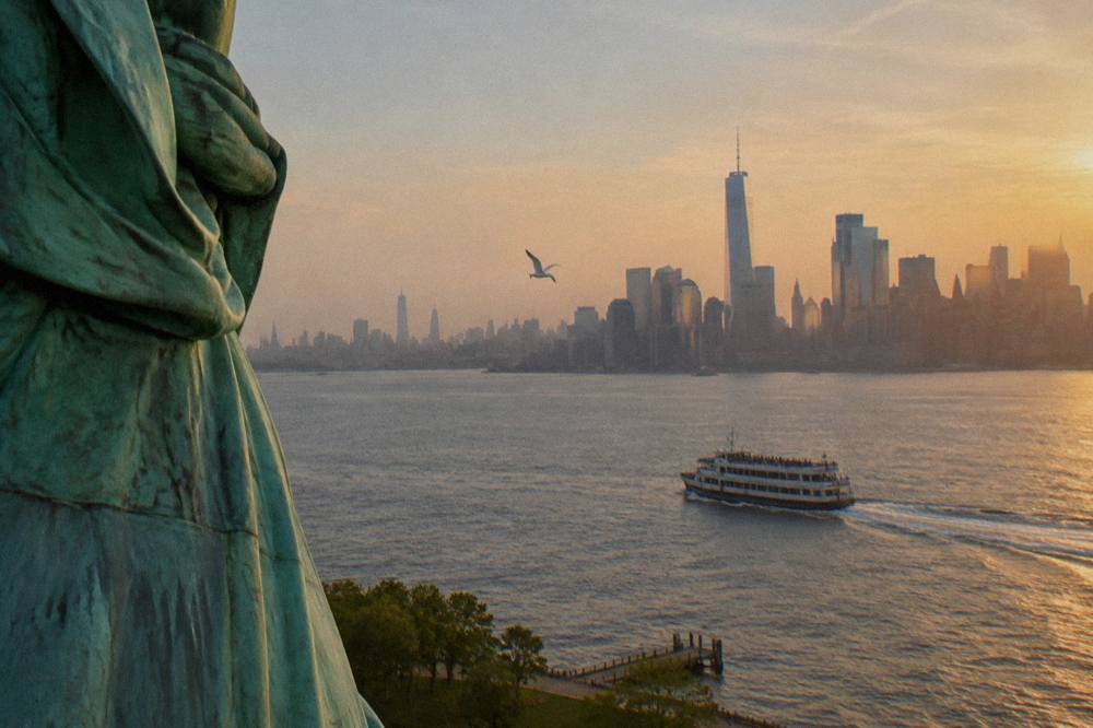 A cruise boat passing the Statue of Liberty in New York Harbor at golden hour