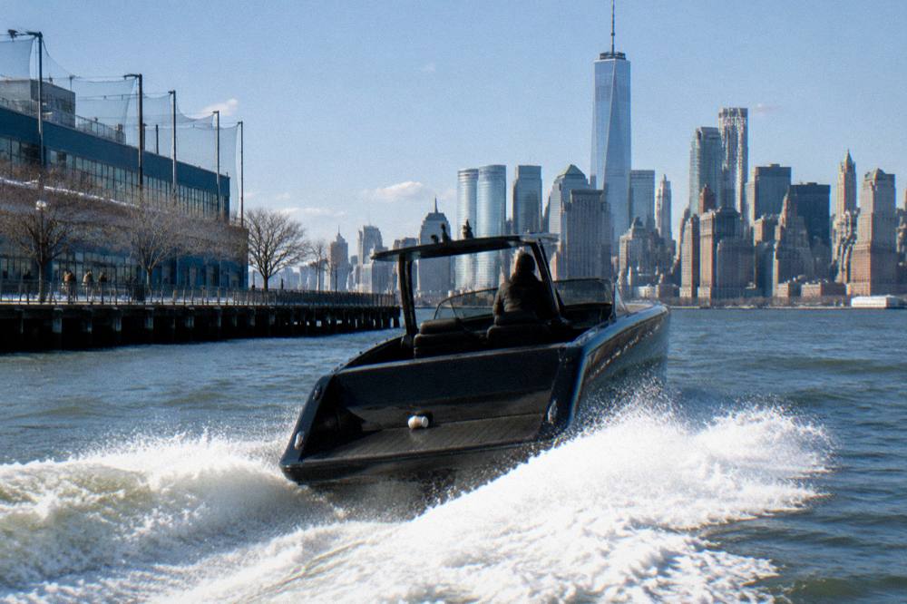 Speedboat cutting across the harbor with spray and the skyline behind.